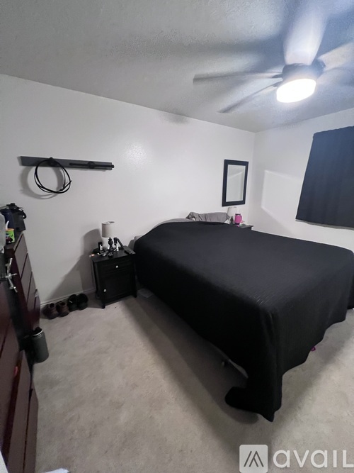 A bedroom with a bed, a fan, and a mirror on the wall.
