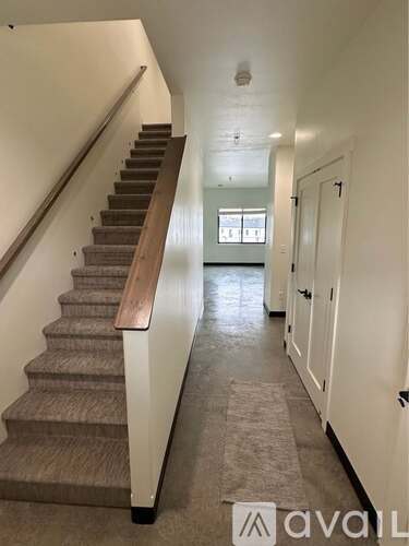 A long hallway with a staircase on the left and a door on the right.