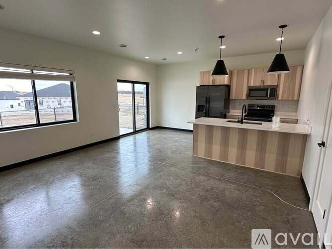 A spacious, empty room with a kitchenette and large windows.
