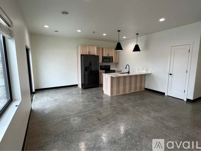 A kitchen area with a black refrigerator, a sink, and a countertop.