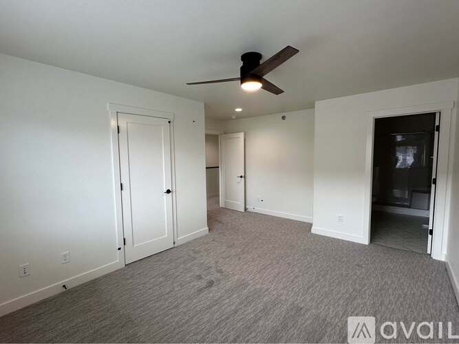 A spacious room with a ceiling fan and carpeted floor.