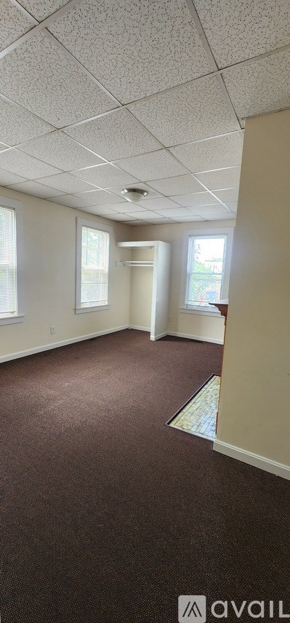 A room with brown carpet and white ceiling tiles.