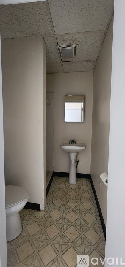 A bathroom with a toilet, sink, and a window.
