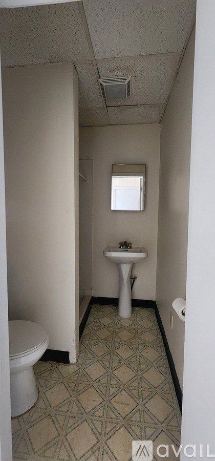 A bathroom with a toilet, sink, and a window.