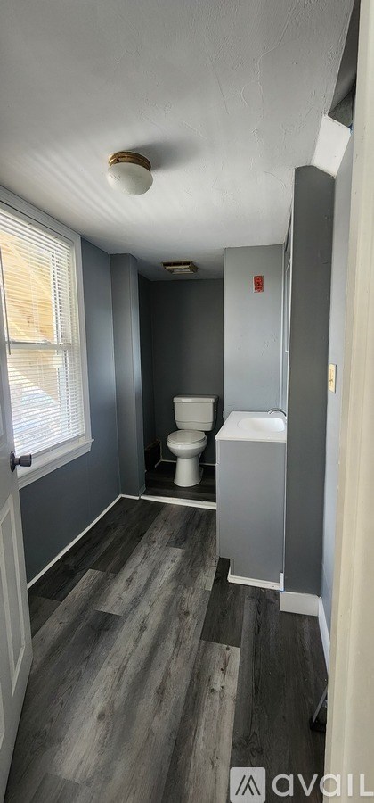 A bathroom with a toilet, sink, and window.