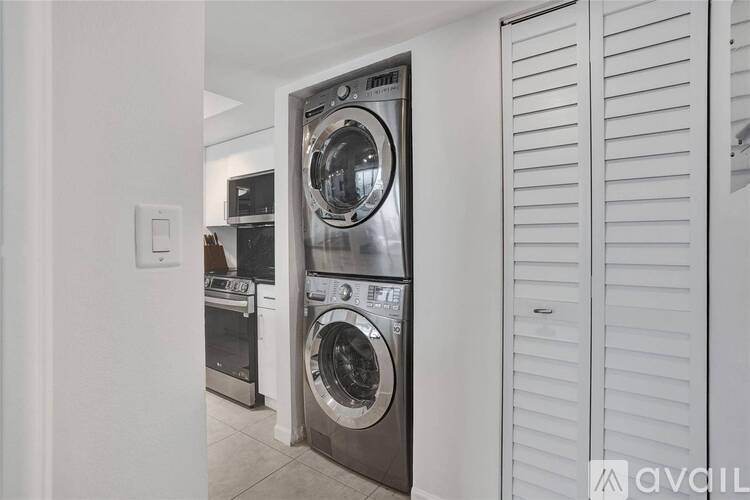 A modern laundry room with a washer and dryer built into the cabinetry.