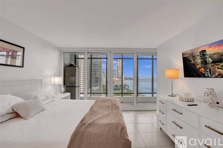 A bedroom with a large bed and a view of the city through the window.