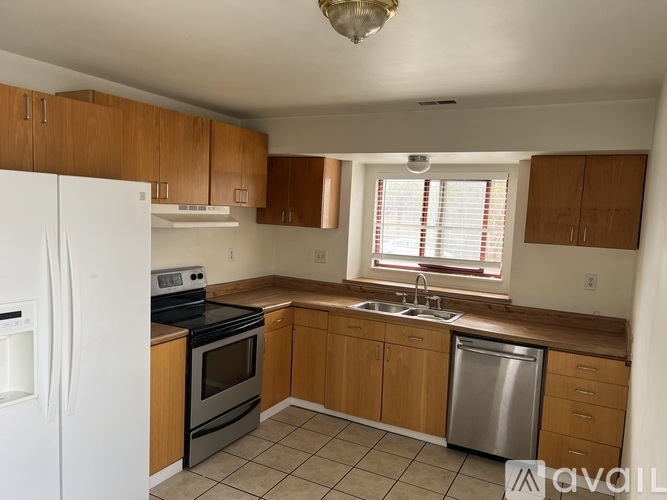 A kitchen with a white fridge and tiled floor.