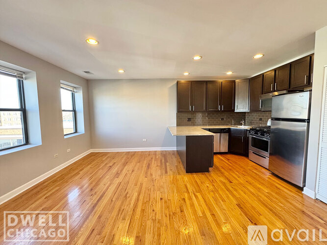 A spacious kitchen with wooden floors and stainless steel appliances.