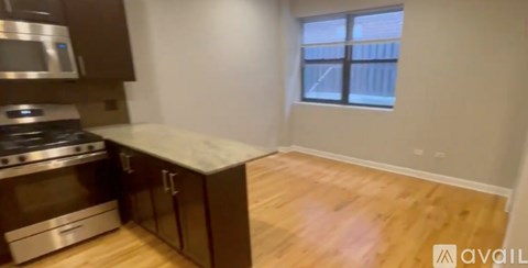 A spacious kitchen with wooden floors and stainless steel appliances.