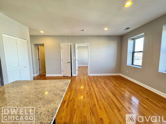A spacious room with wooden flooring and white walls.