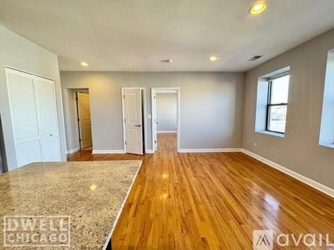 A spacious room with wooden flooring and white walls.