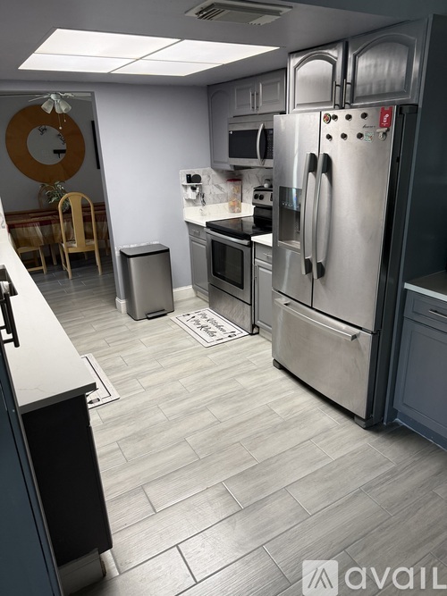 A kitchen with a stainless steel refrigerator and a black chair.