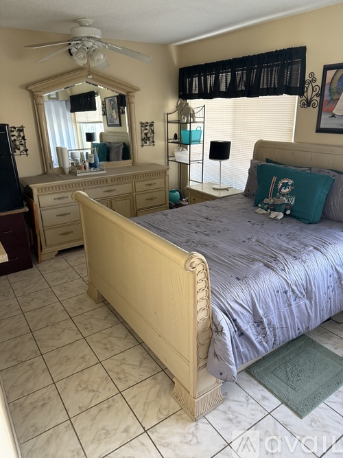 A bedroom with a bed, two drawers, and a mirror on the wall.