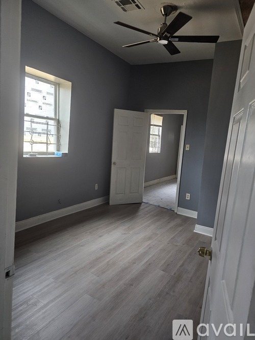 A room with a ceiling fan and light, a door, and a window with blinds.