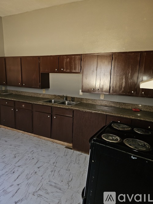 A kitchen with a black stove and brown cabinets.