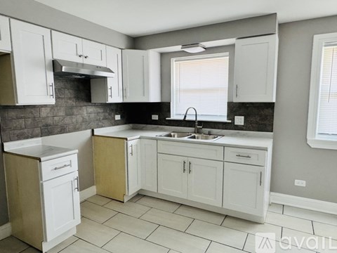 A kitchen with white cabinets and a black countertop.