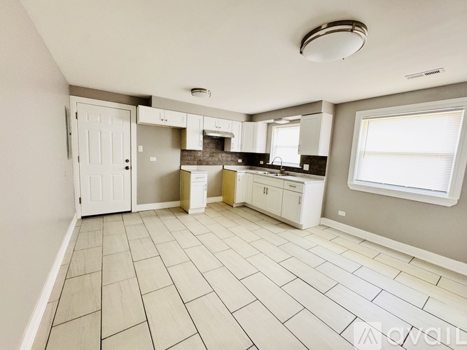A kitchen with white tile flooring and white appliances.