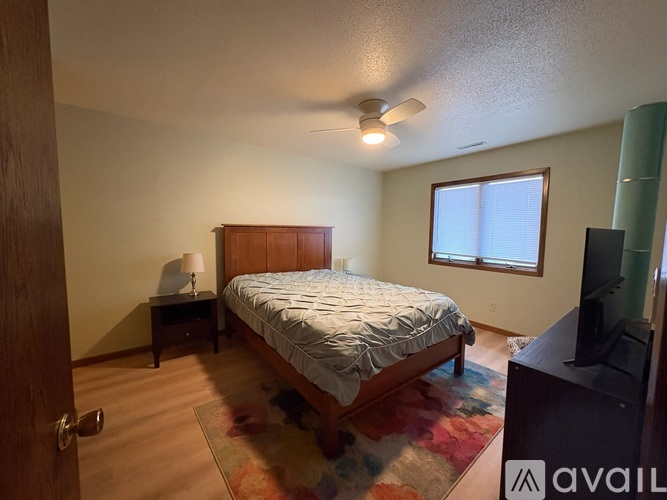 A bedroom with a bed, a ceiling fan, and a rug.