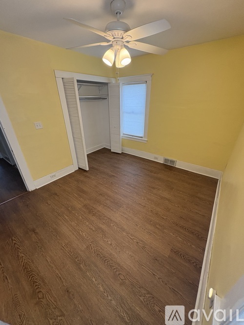 A room with a ceiling fan and wooden flooring.