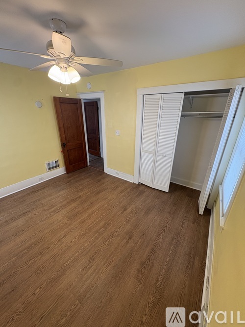 A room with a ceiling fan and wooden flooring.