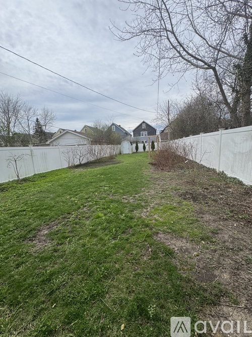 A grassy area with a white fence and a house in the background.