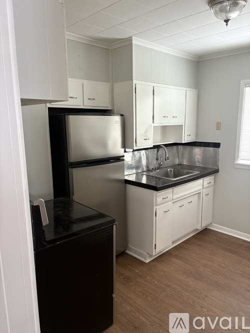 A kitchen with white cabinets and a black fridge.