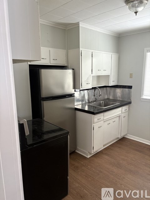 A kitchen with white cabinets and a black fridge.