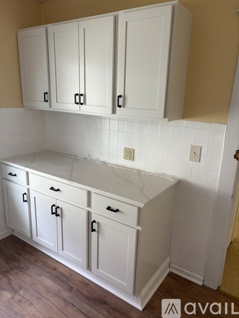 A kitchen with white cabinets and a marble countertop.