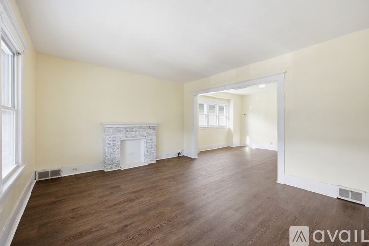 A spacious room with a fireplace and wooden flooring.