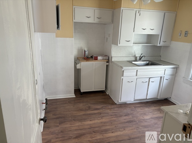 A kitchen with white cabinets and a wooden floor.