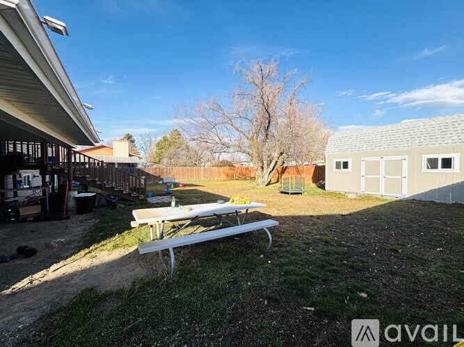 A picnic table is in the foreground of a yard with a building in the background.