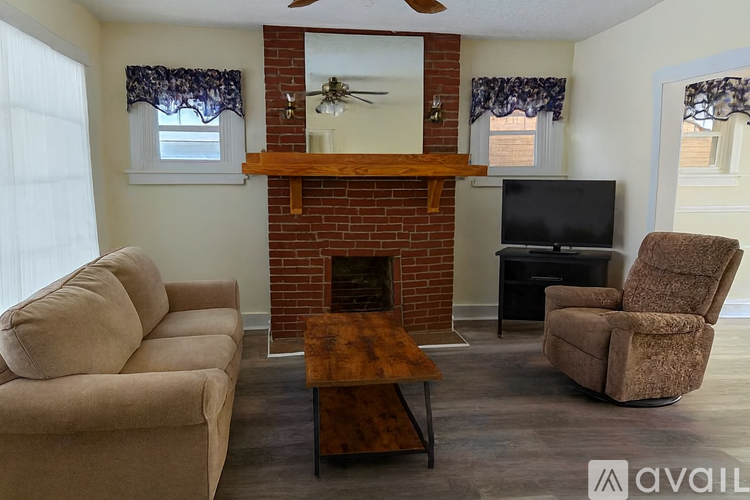 A living room with a fireplace, a couch, a chair, and a television.