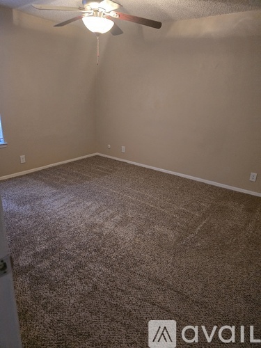 A room with a carpeted floor and a ceiling fan.