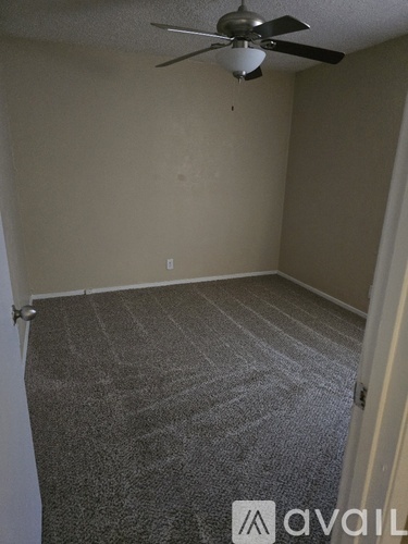 A room with a ceiling fan and carpeted floor.