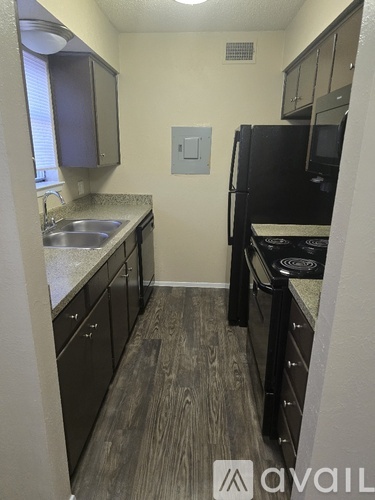 A kitchen with black appliances and brown cabinets.