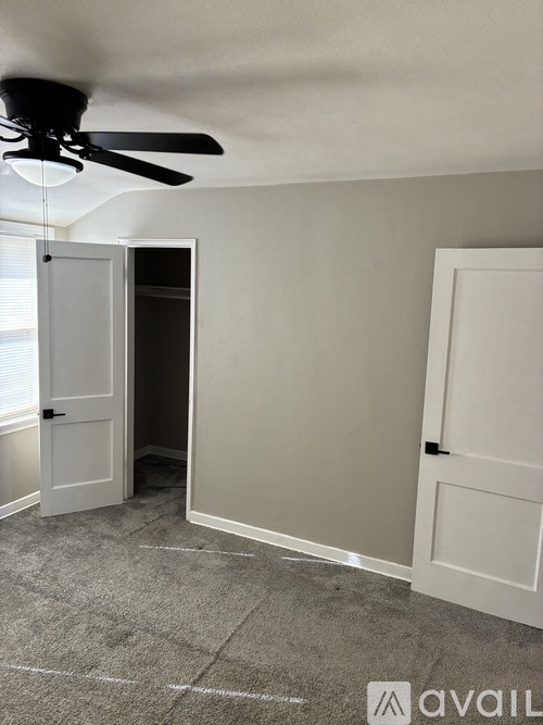A room with a ceiling fan and two doors, one of which is open.