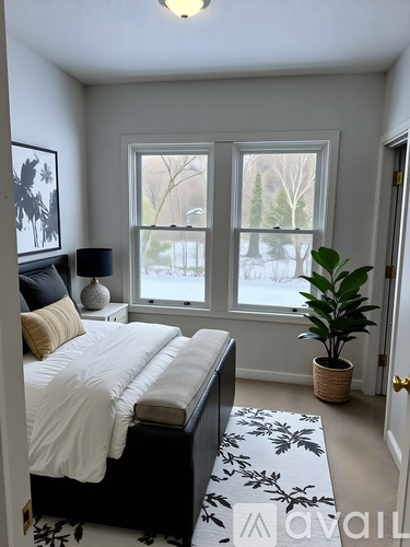 A bedroom with a bed, a plant, and a window.