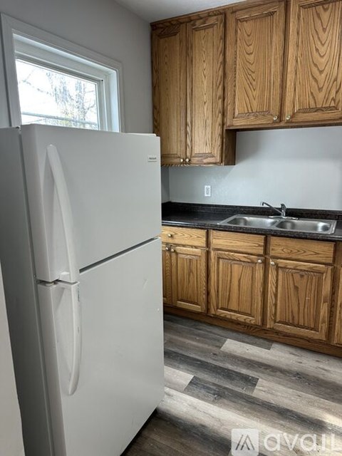 A white refrigerator stands in a kitchen with wooden cabinets.