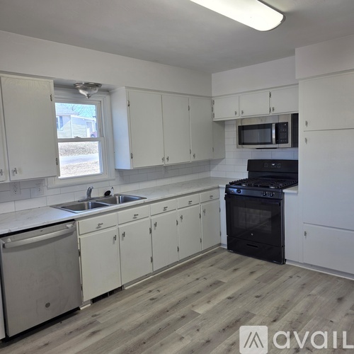 A kitchen with white cabinets and a black stove top oven.