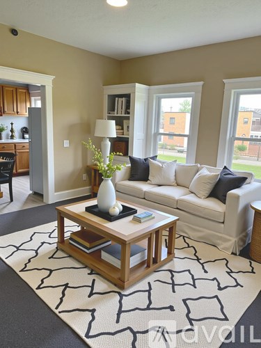 A living room with a white couch and a coffee table with a vase of flowers on it.