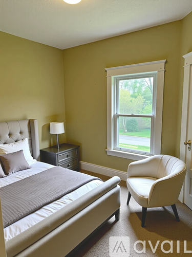 A bedroom with a bed, chair, and window.