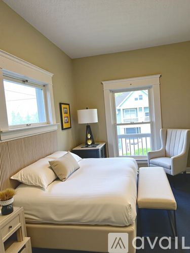 A bedroom with a bed, nightstand, and chair.