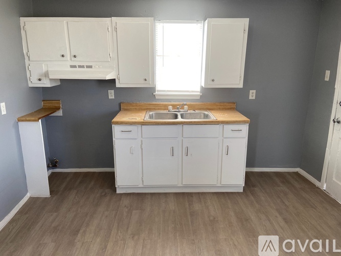 A kitchen with white cabinets and a wooden countertop.