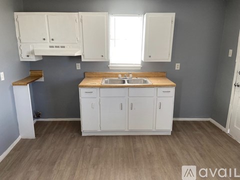 A kitchen with white cabinets and a wooden countertop.