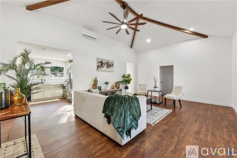 A living room with a white couch and a green throw blanket.