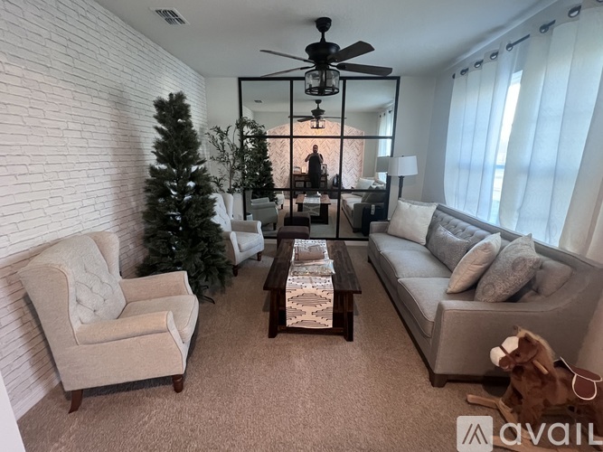 A living room with a Christmas tree and a ceiling fan.