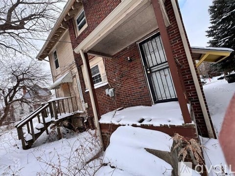 A house with a snow-covered ground and a tree in the background.