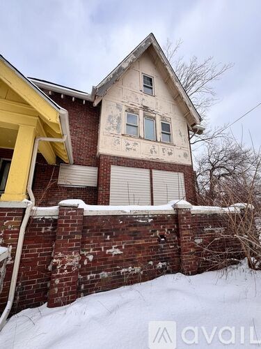 A house with a yellow front and a brick wall.