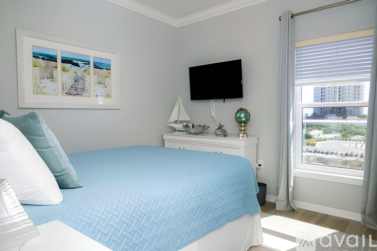 A bedroom with a blue bedspread and a white nightstand with a TV on top.